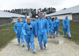 Group of students walking through farm with blue hazmat suits on
